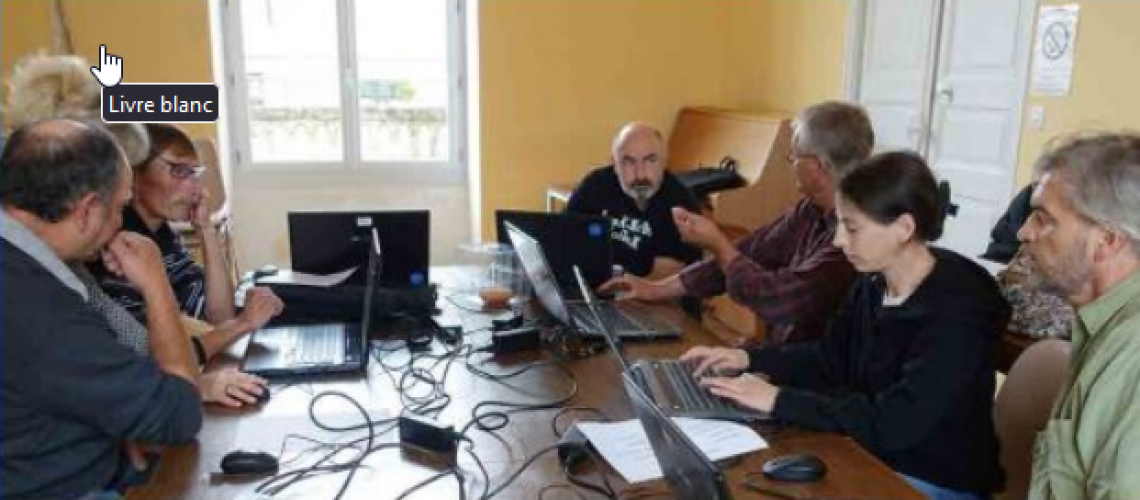 Plusieurs personnes autour d'une table sur lesquels sont posés des ordinateurs portables. Elles semblent discuter entre elles et réfléchir.